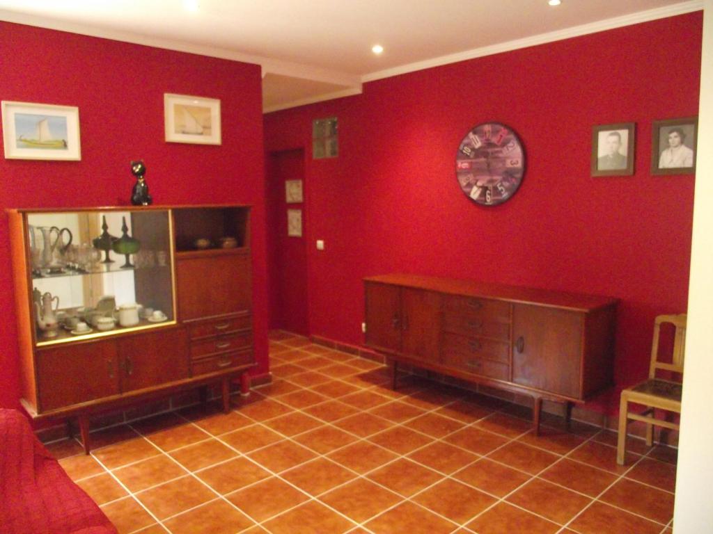 a living room with a red wall with a cabinet and a clock at "A Casa dos Avôs" Suites & Breakfast in Lagos
