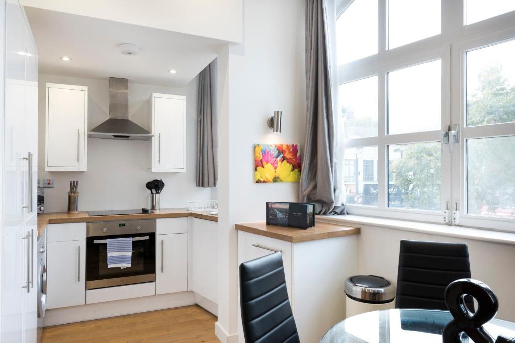 a kitchen with white cabinets and a table and chairs at StayInn Old Street in London