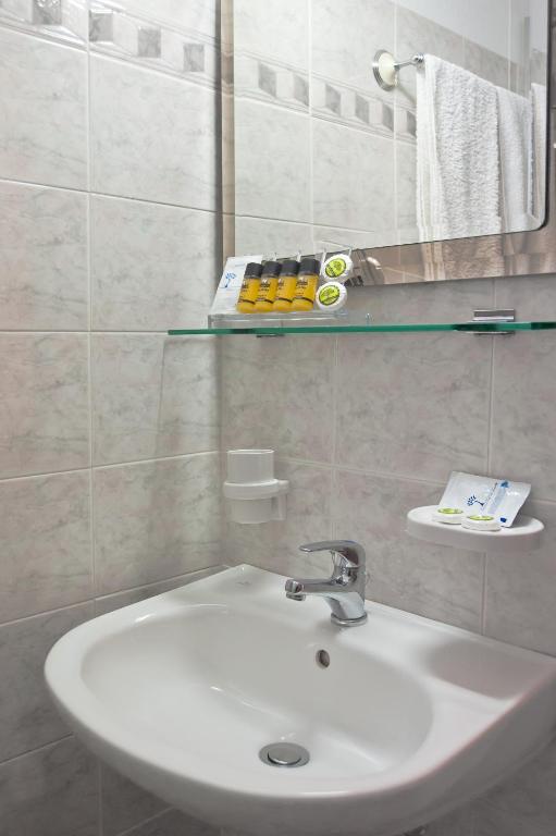 Un baño con un lavabo blanco y un espejo. en Hermes Delphi Hotel, en Delfos
