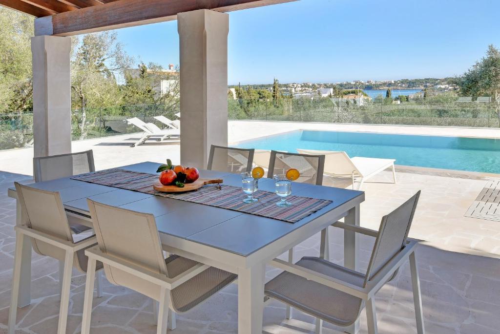 une table bleue et des chaises sur une terrasse avec piscine dans l'établissement Villa Corso, à Portocolom