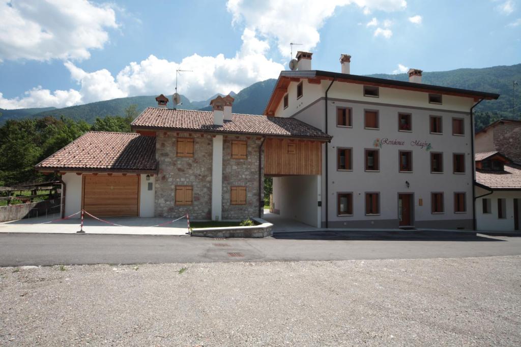 a large white building with mountains in the background at Albergo diffuso Valcellina e Val Vajont in Claut in Claut