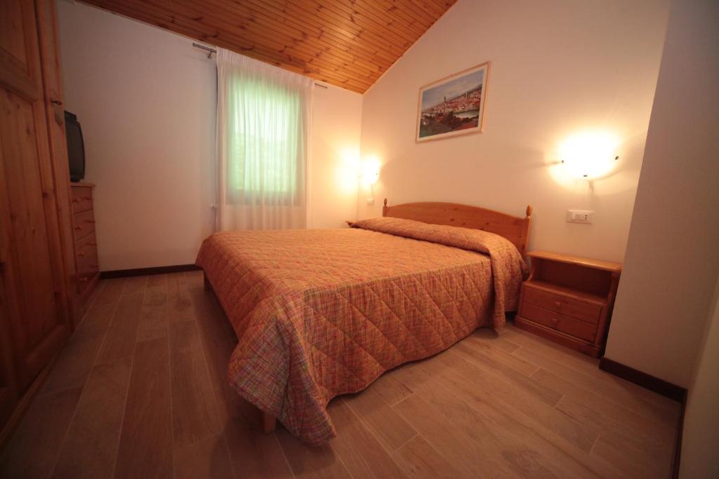 a bedroom with a bed with a orange bedspread at Albergo diffuso Valcellina e Val Vajont in Claut in Claut
