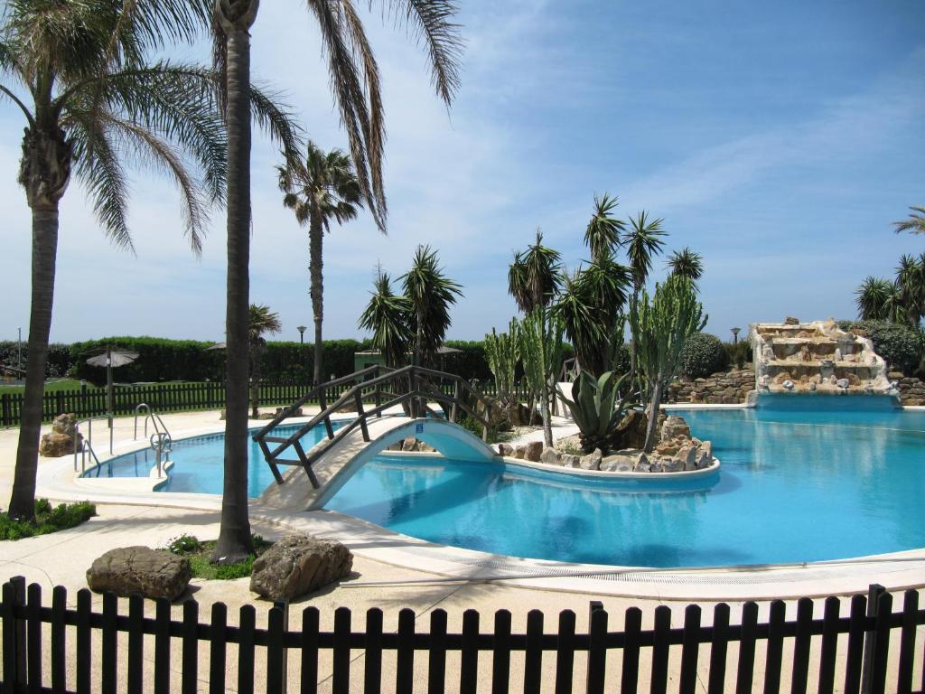 a pool at the resort with palm trees at Las Casas de Mar Atlanterra in Zahara de los Atunes