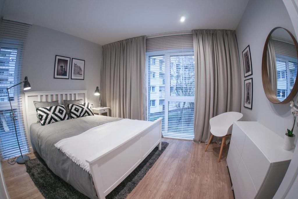 sypialnia z dużym białym łóżkiem i lustrem w obiekcie Barson Apartments w Warszawie