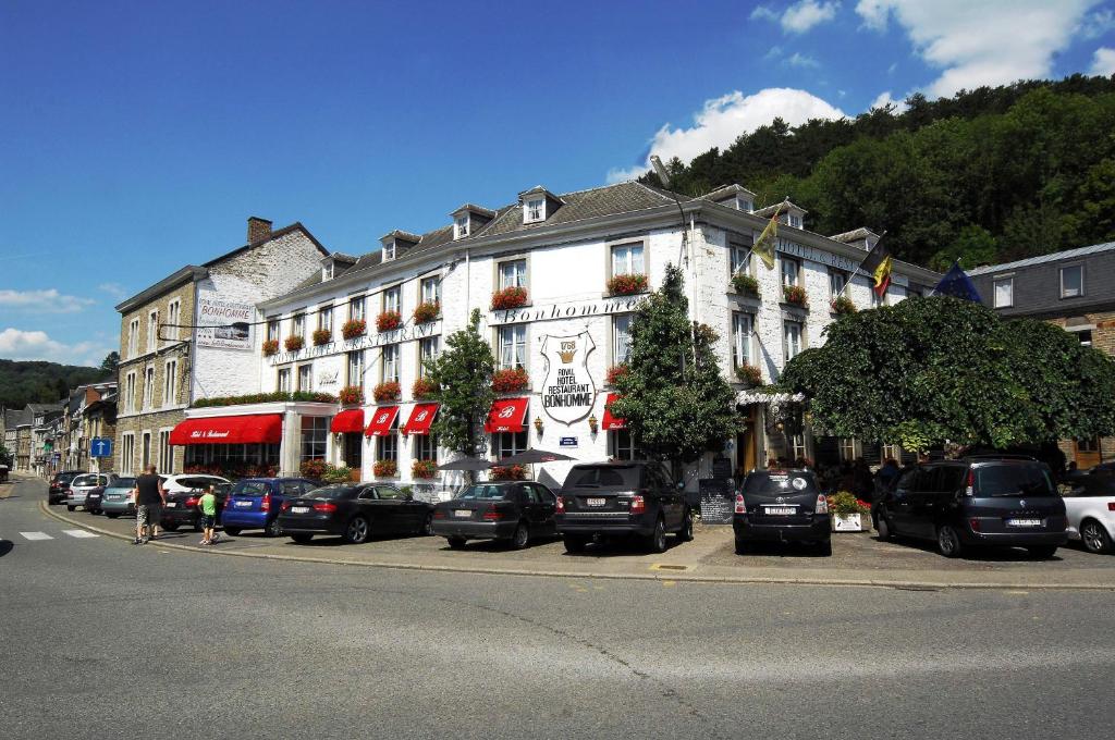 un gran edificio blanco con coches estacionados frente a él en Royal Hotel-Restaurant Bonhomme en Sougné-Remouchamps