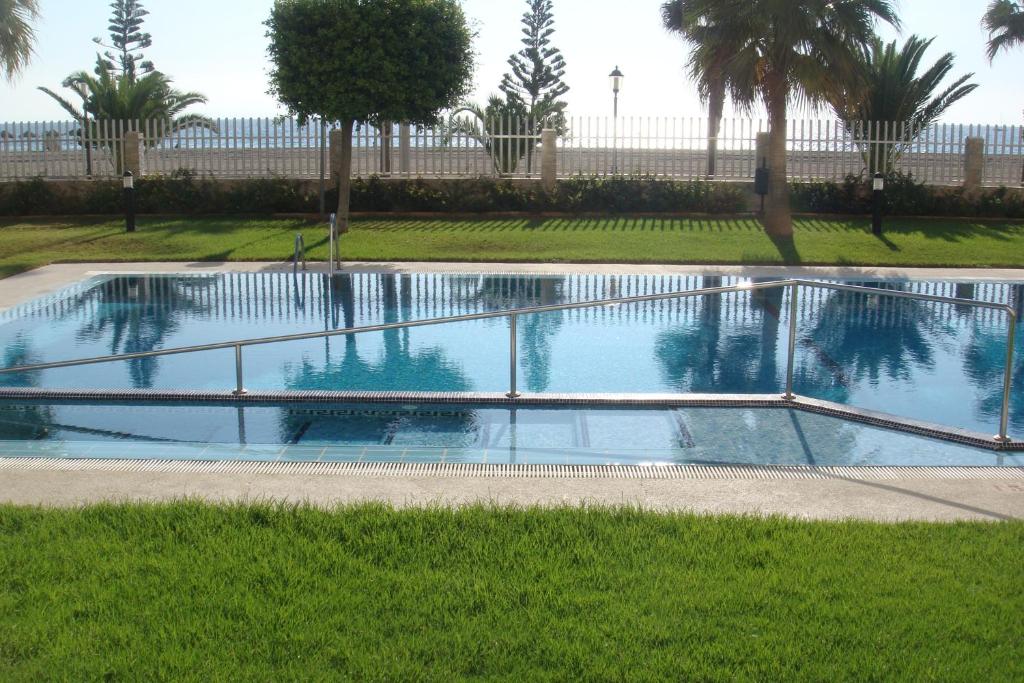 a swimming pool in a park with trees and grass at Primera línea playa in Roquetas de Mar