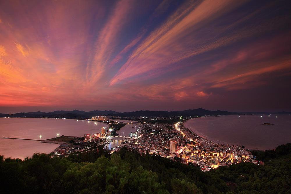 Blick auf die Stadt in der Nacht am Strand in der Unterkunft Huizhou Double Moon Zen Service Apartment in Pingshan