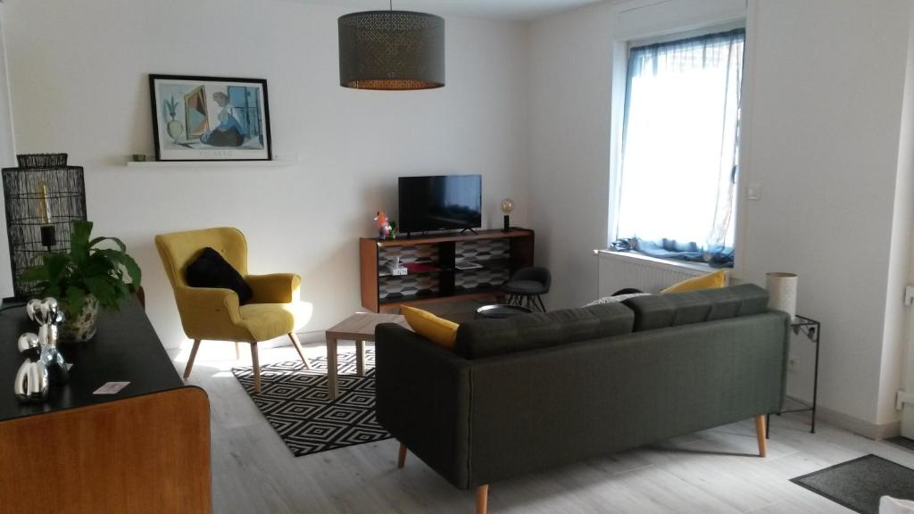 a living room with a couch and chairs and a tv at Pause Messines Chez Anne-Marie in Verlinghem