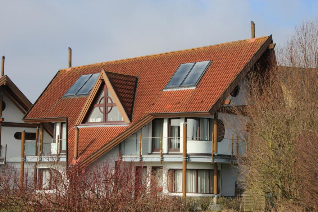 フリードリッヒシュコオクにあるFerienwohnung*** Achtern Diekの太陽電池パネル付赤屋根の家