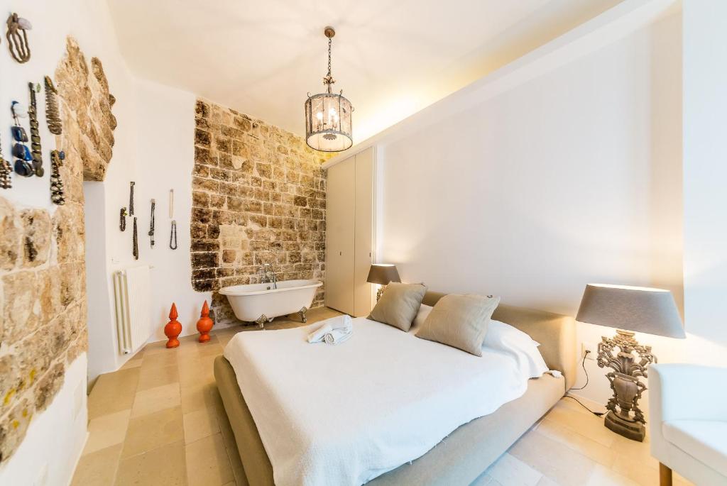 a bedroom with a white bed and a bath tub at Itaca Home to Explorers in Polignano a mare in Polignano a Mare