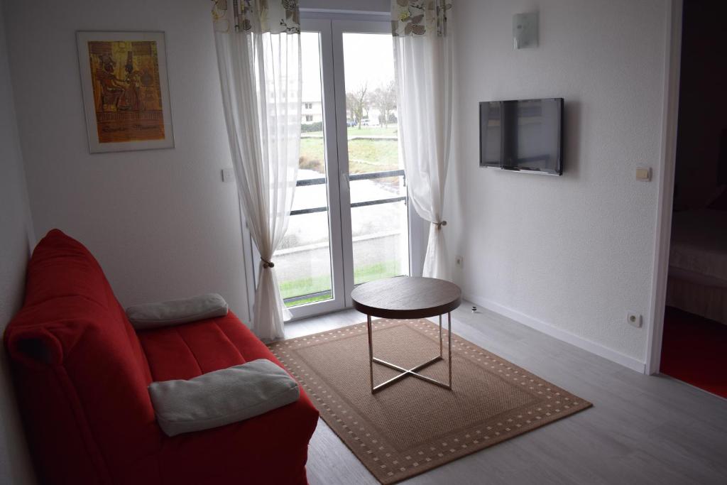 sala de estar con sofá rojo, mesa y ventana en Les 3M, en La Rochelle