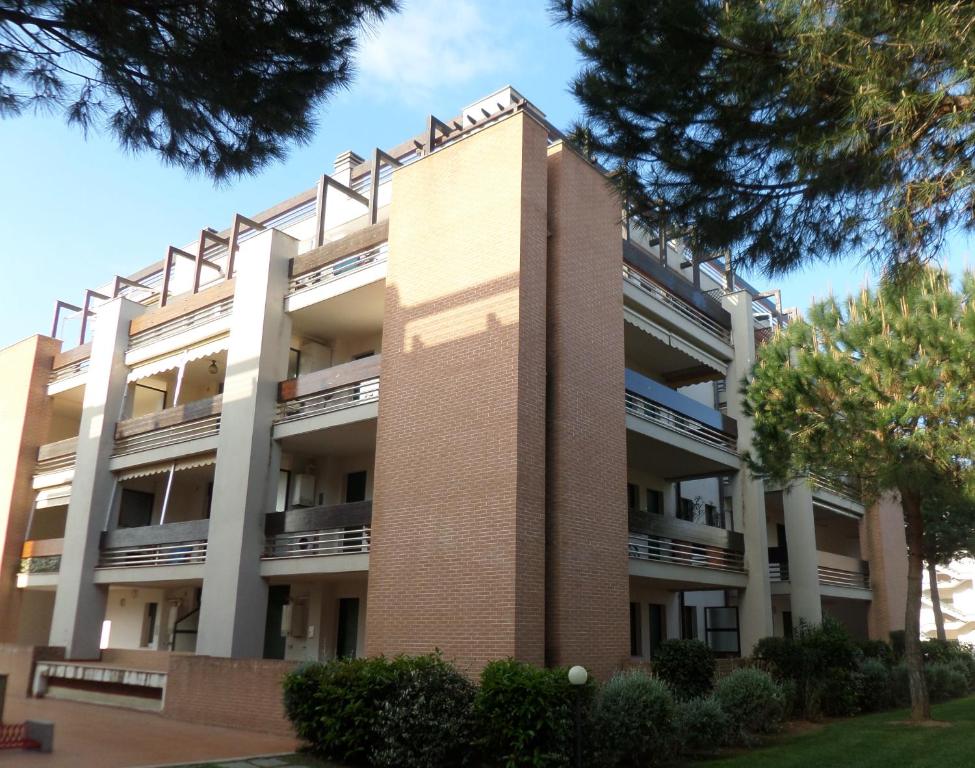un grand bâtiment en briques avec des arbres devant lui dans l'établissement Apartment Anna San Vincenzo, à San Vincenzo