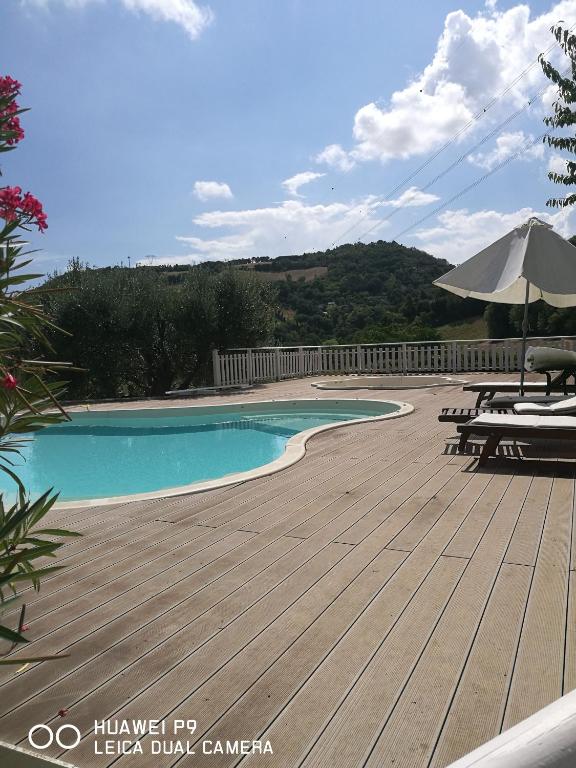 basen z drewnianym tarasem i parasolem w obiekcie Country house "L'isola che non c'è" w mieście Ancona