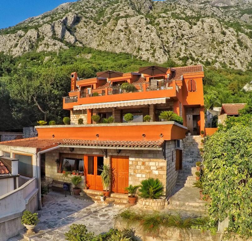 an orange house with a mountain in the background at Apartments Nikčević in Kotor