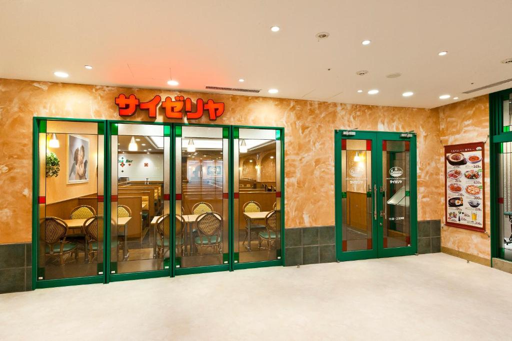 a restaurant with green glass doors and tables at Sotetsu Fresa Inn Tokyo-Toyocho in Tokyo