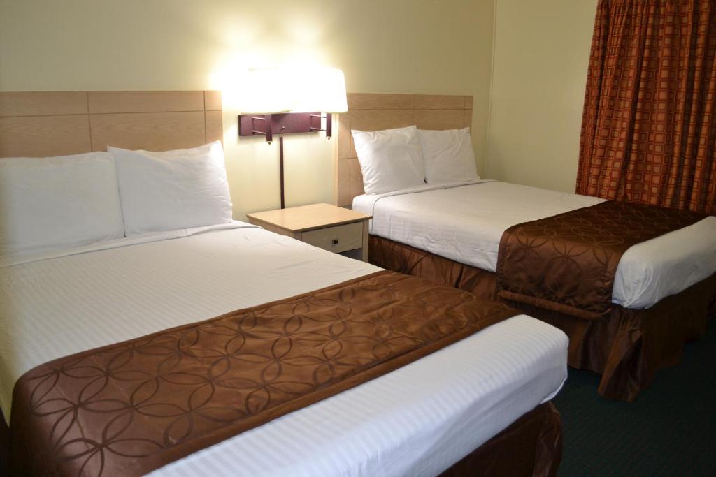 a hotel room with two beds and a lamp at Passport Inn Niagara Falls in Niagara Falls