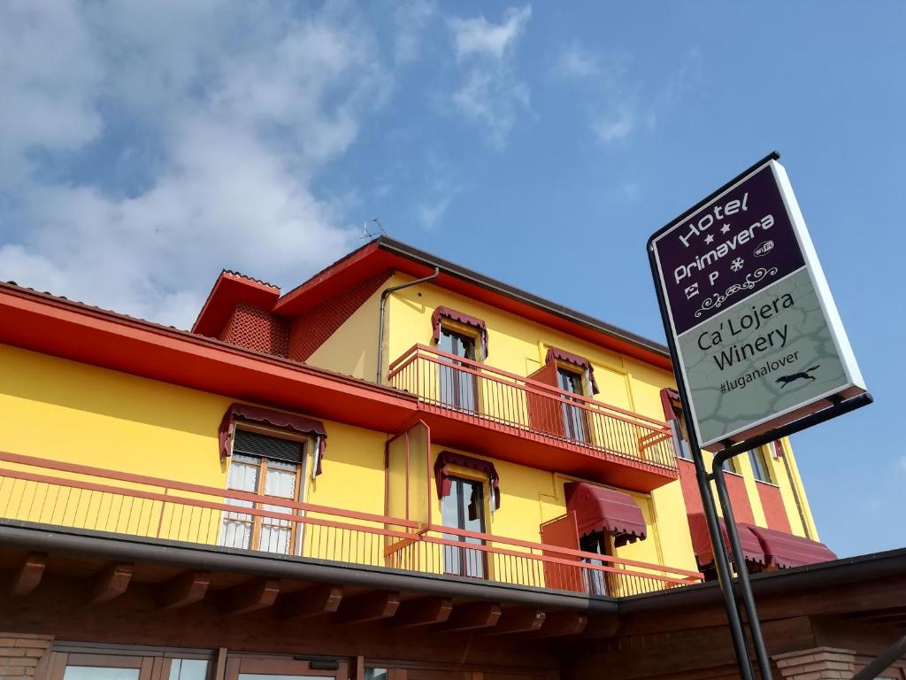 a yellow and red building with a sign in front of it at Hotel Primavera in Peschiera del Garda