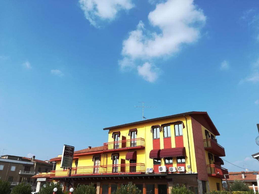 a yellow and red building with a blue sky at Hotel Primavera in Peschiera del Garda
