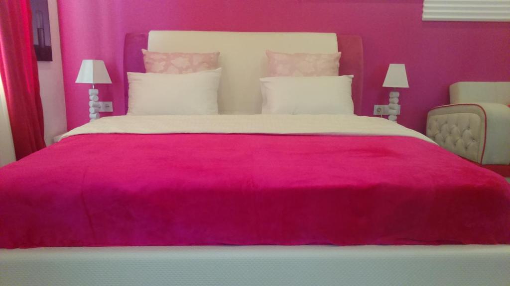 a pink bedroom with a large bed with a red blanket at Pink Apartment near Airport in Nizhnyaya Alekseyevka