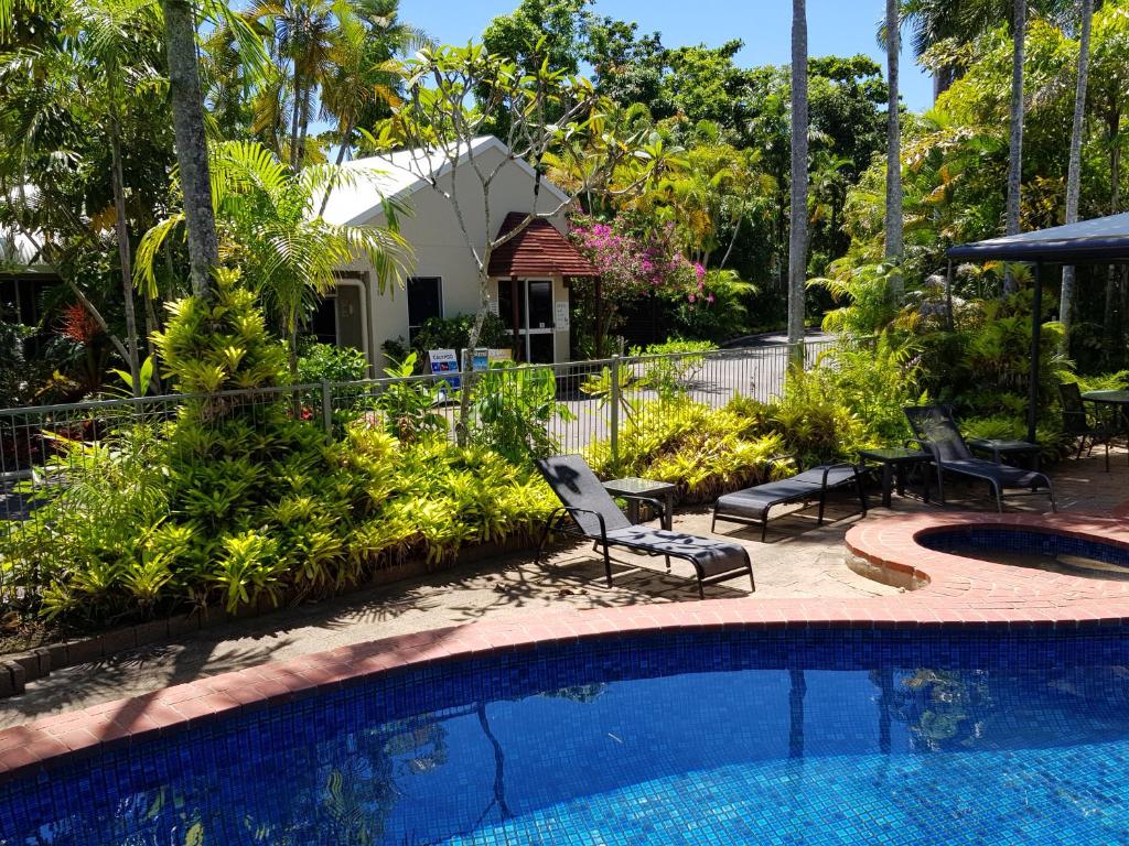 een zwembad met stoelen naast een huis bij Mango Tree Holiday Apartments in Port Douglas
