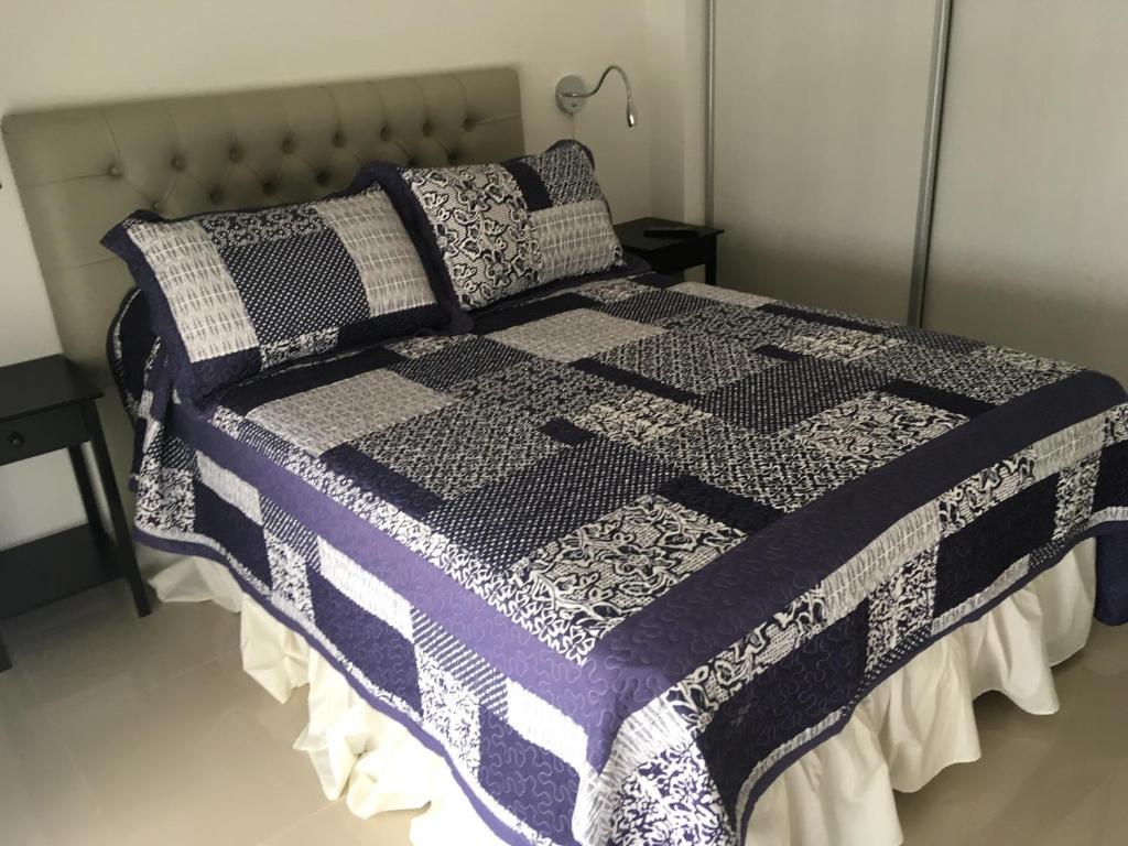 Una cama con un edredón blanco y negro. en Hermoso departamento con piscina en Río Cuarto