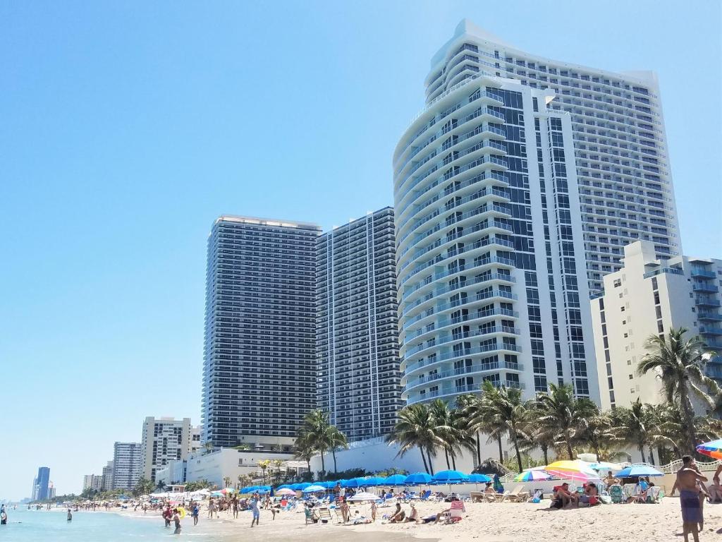 a group of buildings on a beach with palm trees at On The Beach - Lux 2 Bedroom Miami in Hollywood