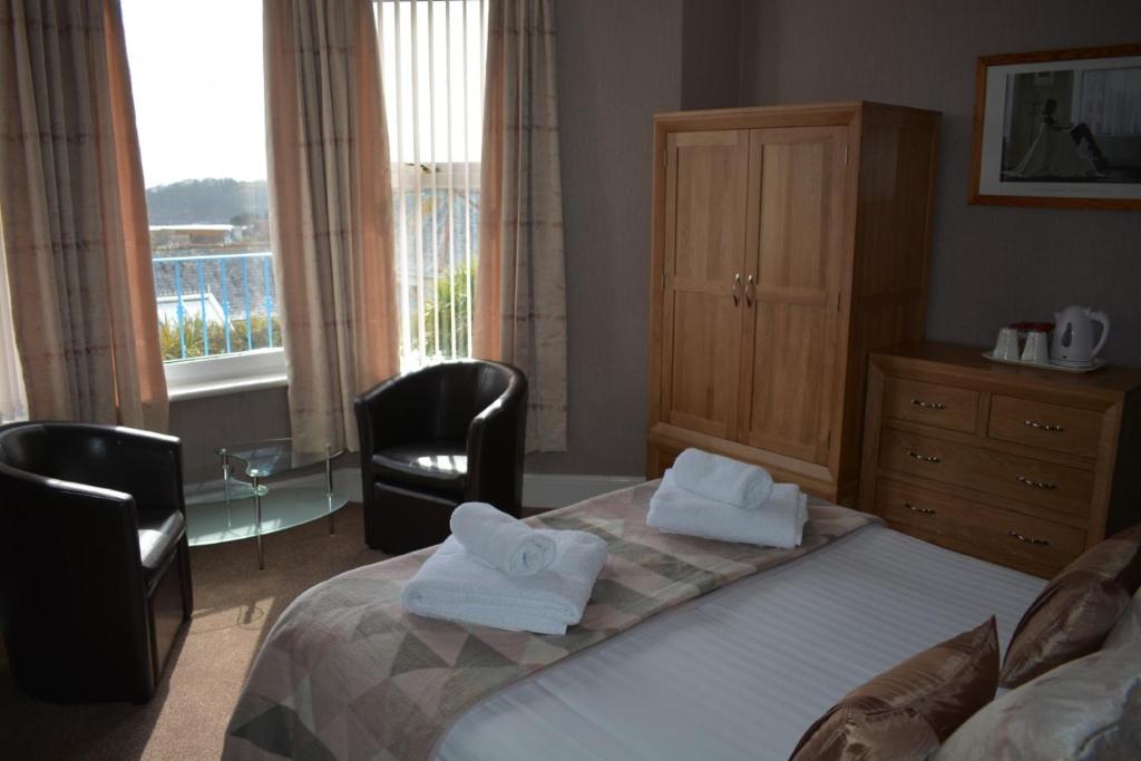 a bedroom with a bed with two towels on it at Cotswold House in Falmouth