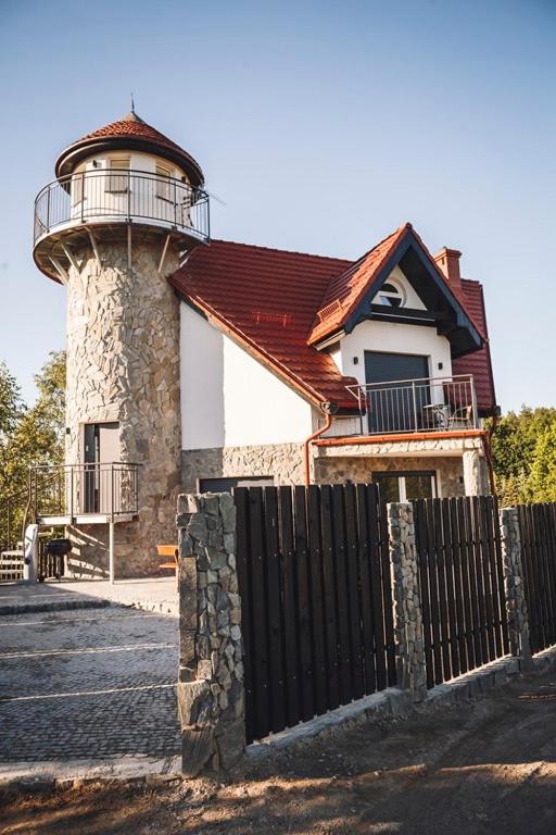 a building with a lighthouse behind a fence at Villa Tower Nad Jeziorem Nyskim in Skorochow