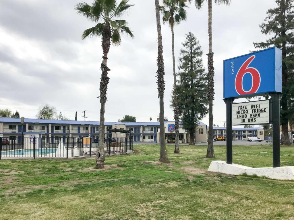una señal frente a un edificio con palmeras en Motel 6-Visalia, CA, en Visalia