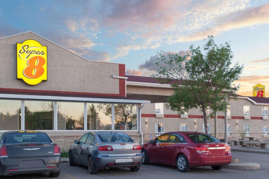 drie auto's geparkeerd buiten een fastfoodrestaurant bij Super 8 by Wyndham Brandon MB in Brandon