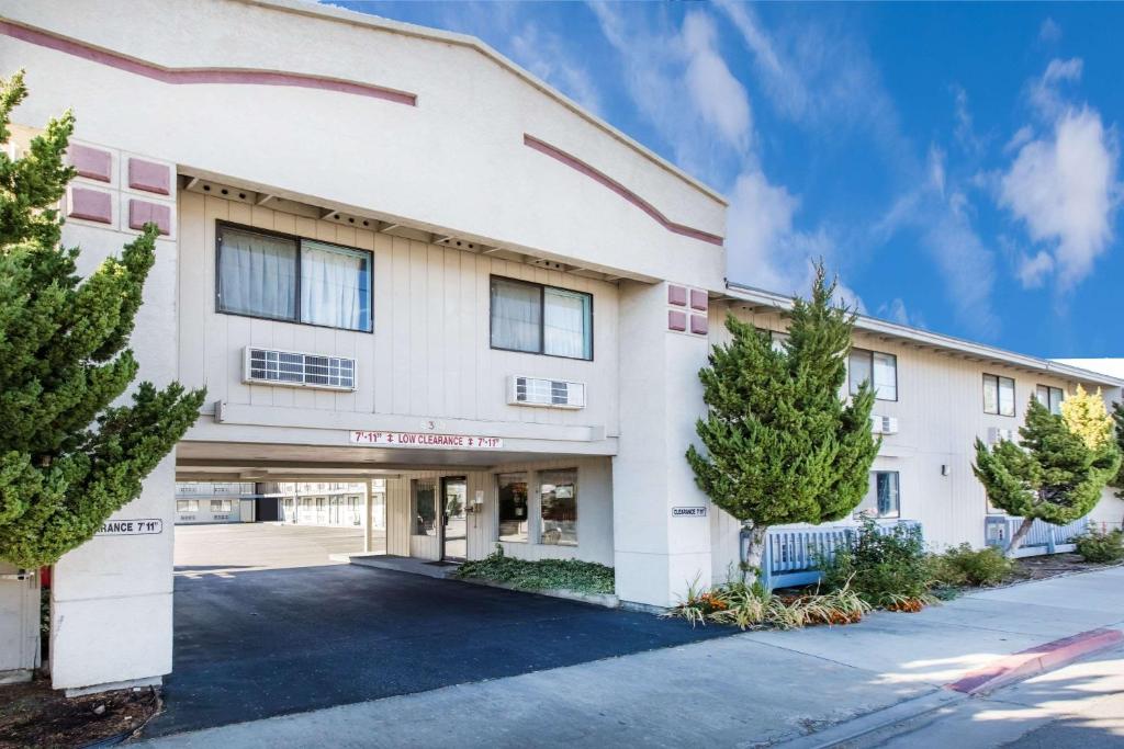 a large white building with trees in front of it at Super 8 by Wyndham Bishop in Bishop