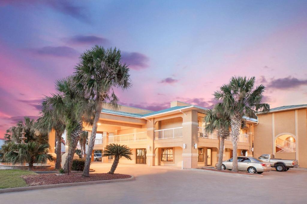 a large building with palm trees in front of it at Super 8 by Wyndham Corpus Christi in Corpus Christi