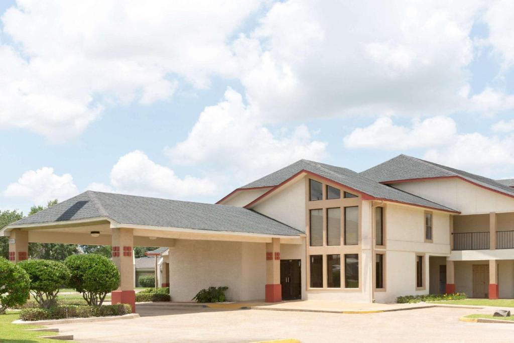 un grand bâtiment blanc avec un toit gris dans l'établissement Super 8 by Wyndham Bossier City/Shreveport Area, à Bossier City