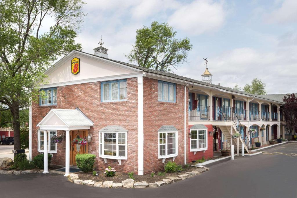 un edificio de ladrillo rojo con un cartel. en Super 8 by Wyndham Sturbridge, en Sturbridge