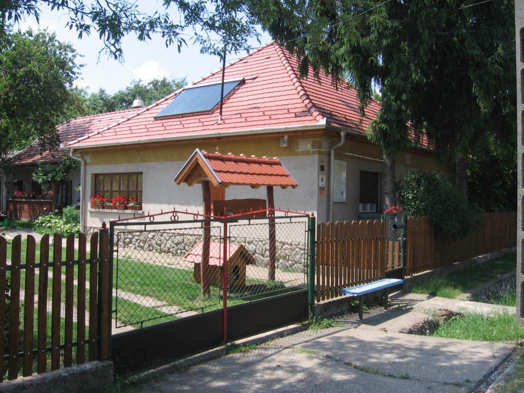 ein Haus mit einem Zaun mit einer Schaukel in der Unterkunft Manó Vendégház in Pázmánd