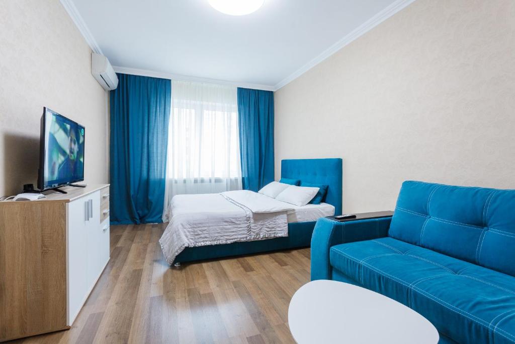 Una sala de estar con un sofá azul y una cama. en Cosy Apartment at Pozniaky, en Kiev