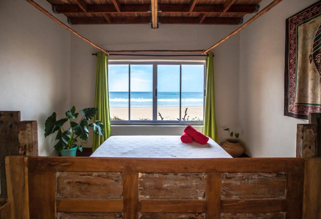 プライア・ド・トフォにあるPura Vida Tofo Beach Housesのビーチの景色を望むベッドルーム1室(ベッド1台付)