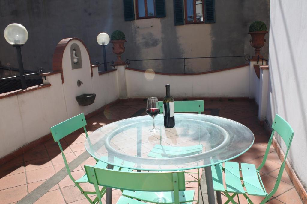un tavolo in vetro con una bottiglia di vino e due sedie di S.Zanobi courtyard house w/ terrace a Firenze