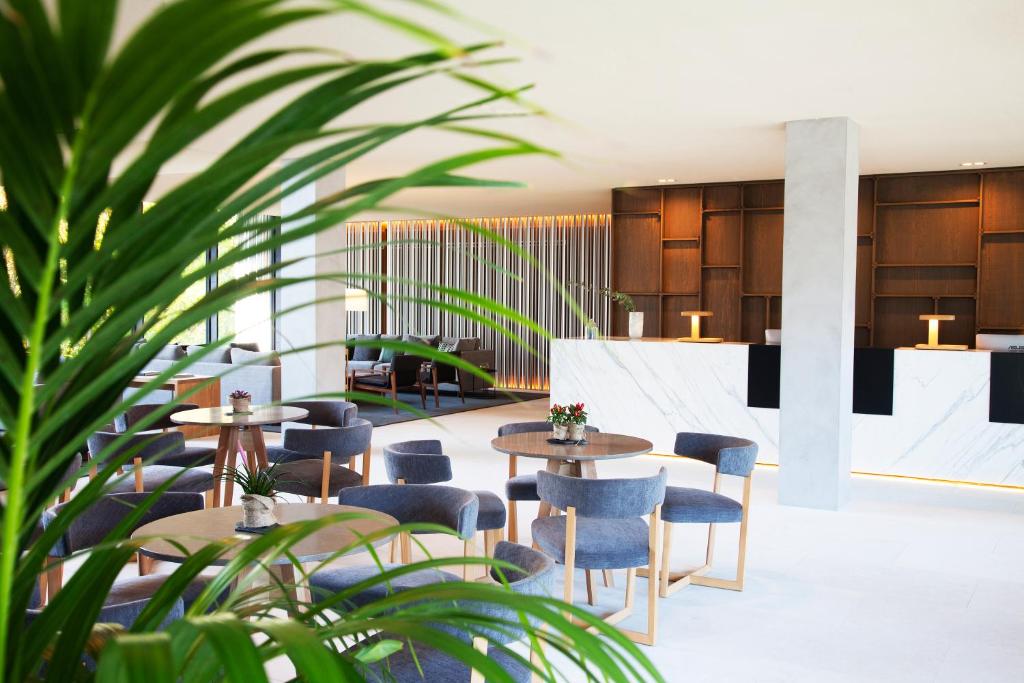 a hotel lobby with tables and chairs and plants at Hotel Arima & Spa - Small Luxury Hotels in Donostia-San Sebastián