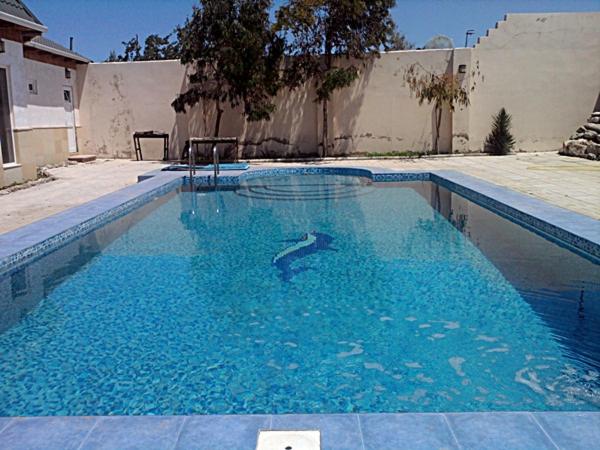 una piscina con acqua blu in un cortile di Shuvelan Cottage House a Şüvǝlǝn