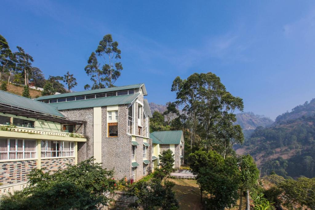 a house on a hill with mountains in the background at Devonshire Greens - The Leisure Hotel and Spa in Munnar