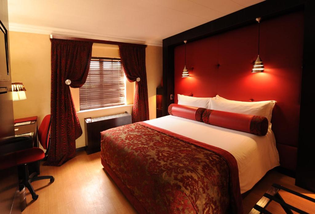 um quarto com uma cama grande e uma parede vermelha em Cycad Guest House em Polokwane