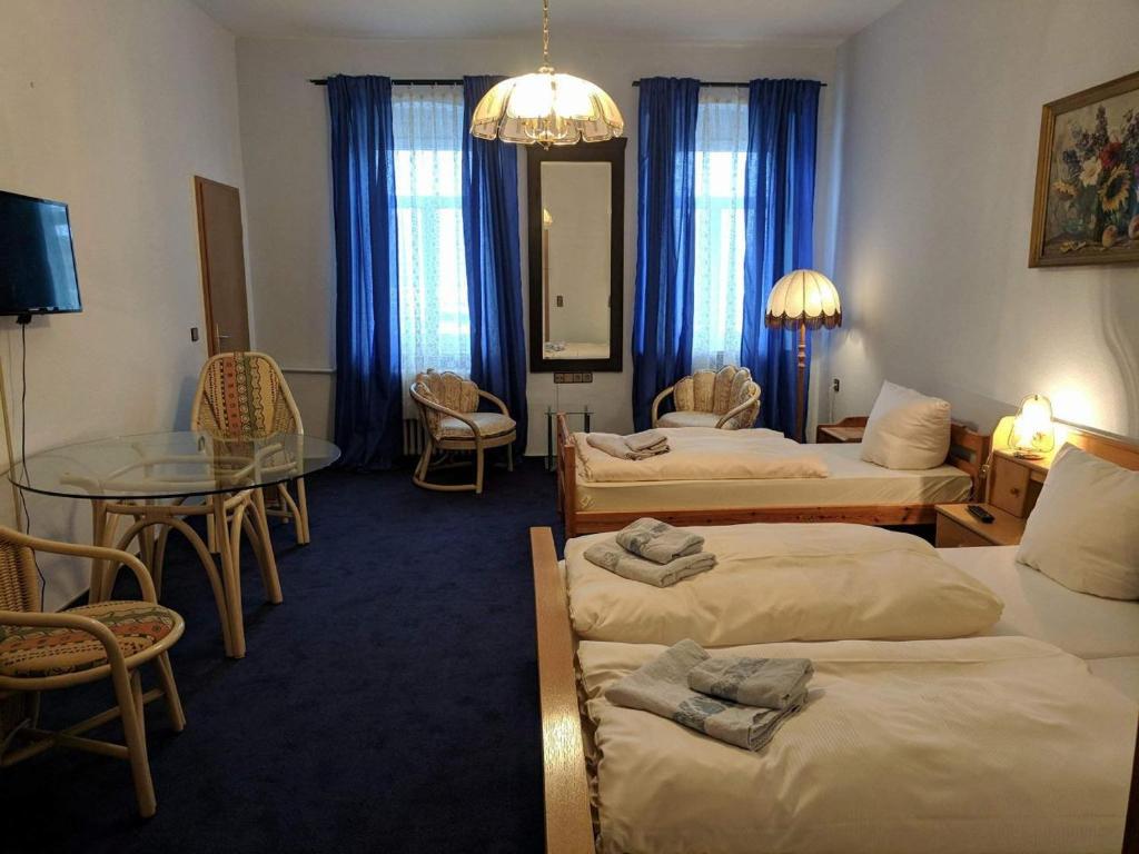 ディポルディスヴァルトにあるBahnhotel Dippoldiswaldeのベッド3台とガラスのテーブルが備わるホテルルームです。