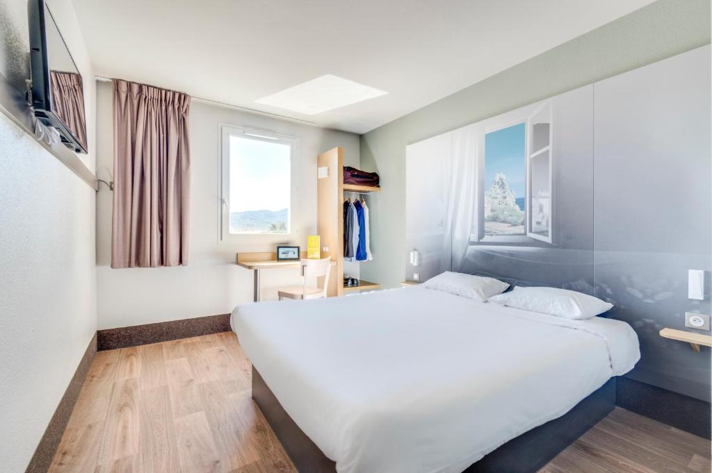 Un dormitorio con una gran cama blanca y una ventana en B&B HOTEL Brignoles, en Brignoles