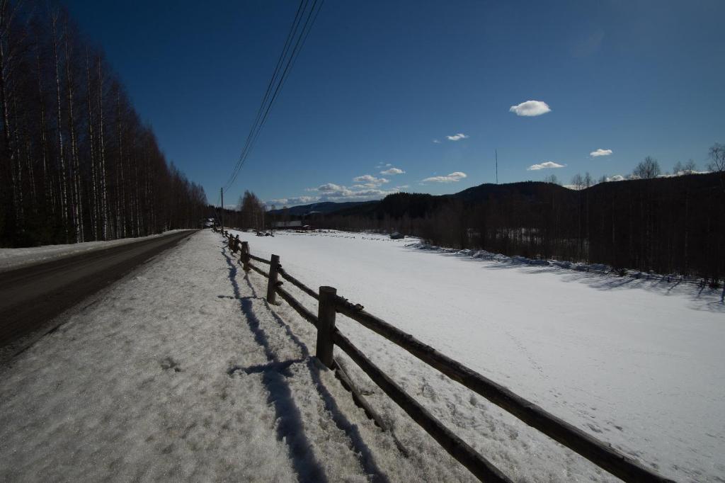 a fence on the side of a snow covered road at Paimentupa in Kolinkylä