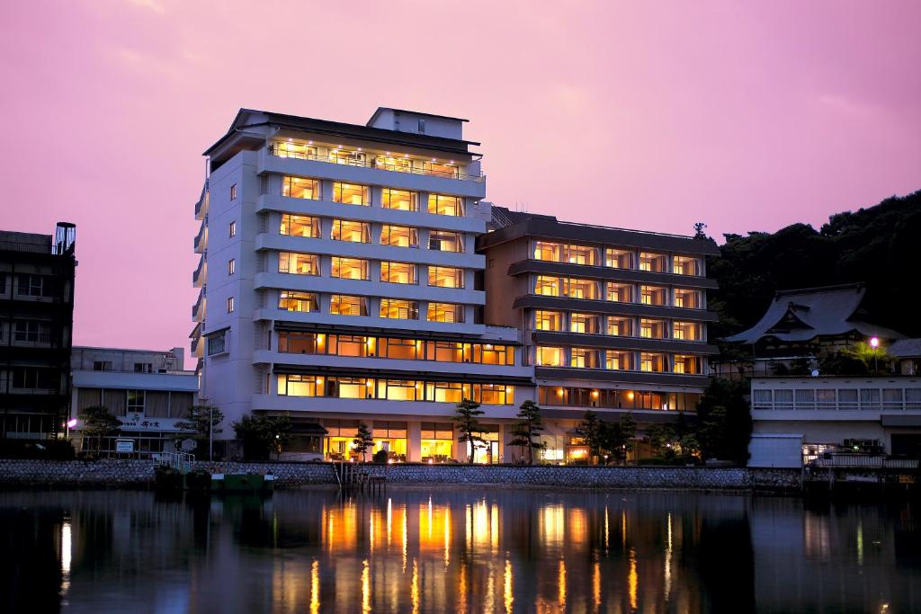a building with lights on in front of a body of water at Sansuikan Kinryu in Hamamatsu