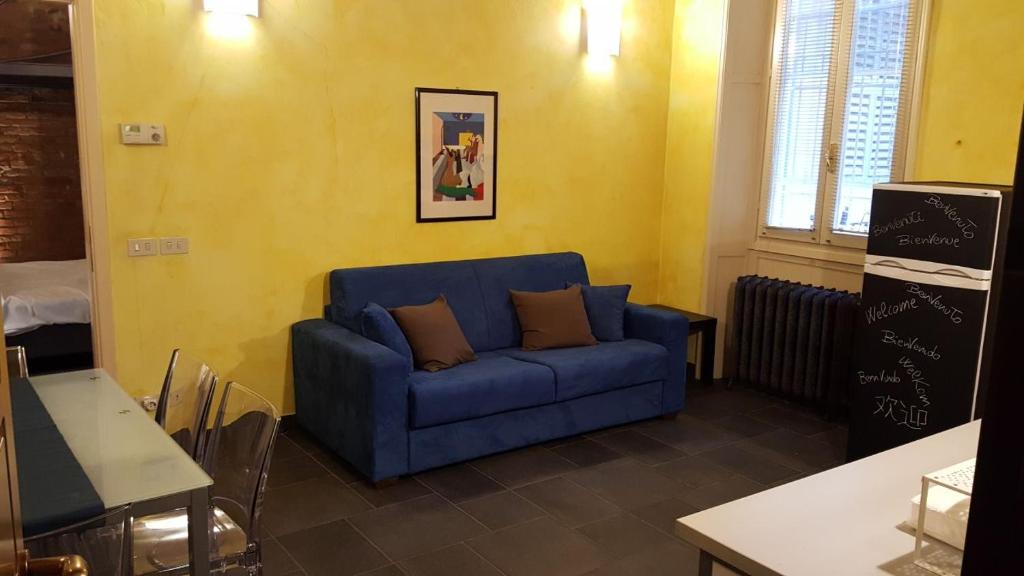 ein Wohnzimmer mit einem blauen Sofa und einer gelben Wand in der Unterkunft "Piazza Vittoria"Pavia SPLENDIDA Dimora in Pavia