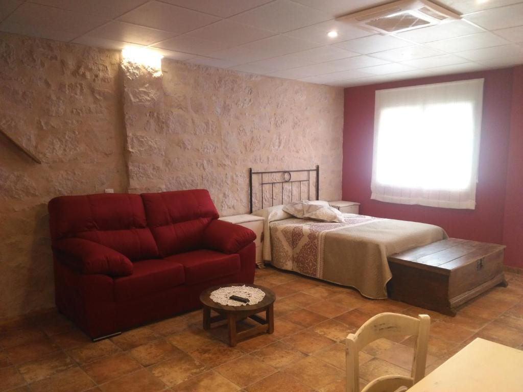 1 dormitorio con 1 cama y 1 sofá rojo en Apartamentos Calanda, en Calanda