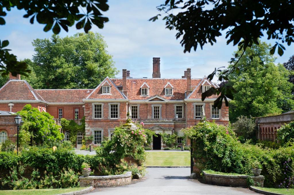 einen Blick nach außen auf ein großes Backsteinhaus mit Büschen in der Unterkunft Lainston House in Winchester