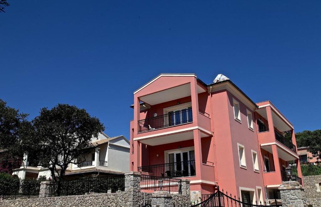 a pink building on top of a stone wall at Kanoni Apartment in Corfu Town